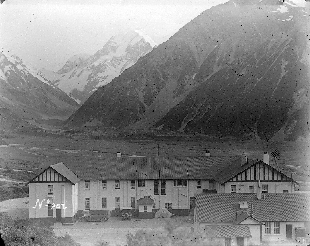 Vintage black and white photo of a large hotel building with mountains in the background.
